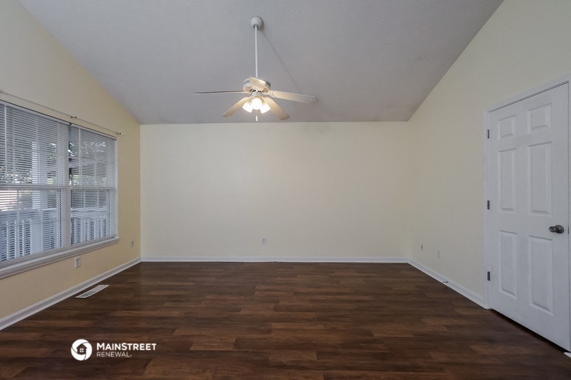 the spacious living room with a ceiling fan and wood flooring