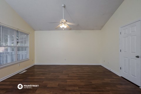 the spacious living room with a ceiling fan and wood flooring