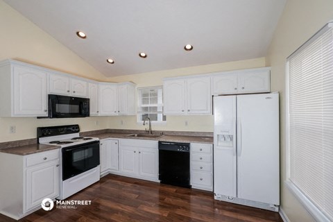 a renovated kitchen with white cabinets and black appliances