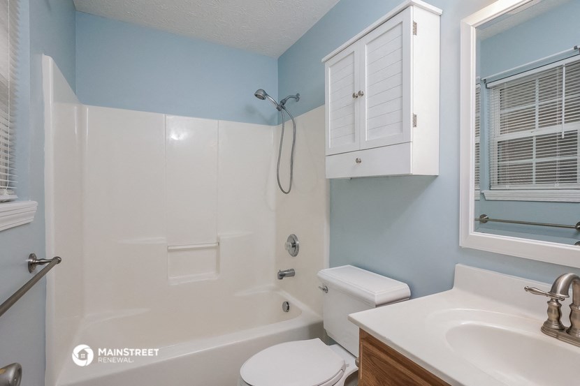 a bathroom with a white tub and a sink and a toilet