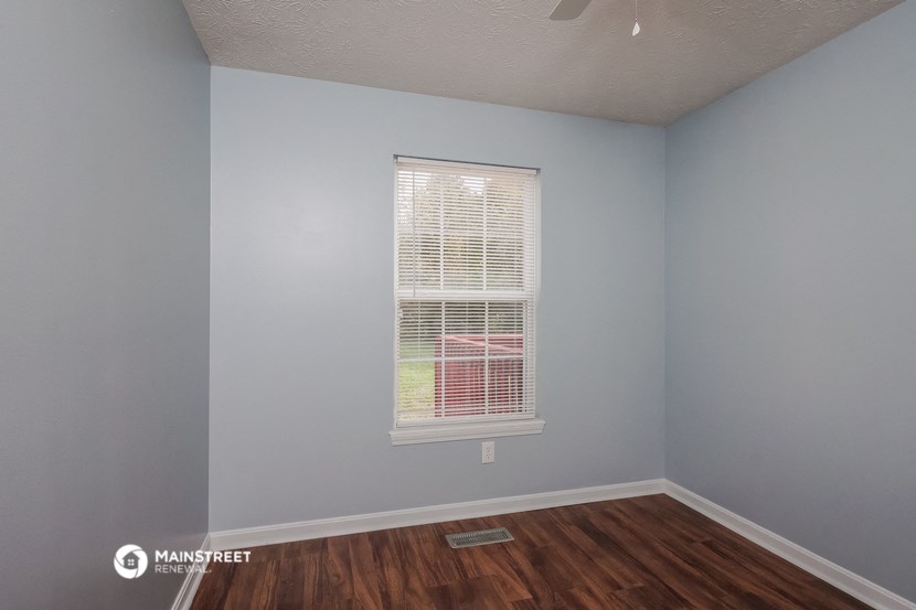 an empty room with a window and wooden floors
