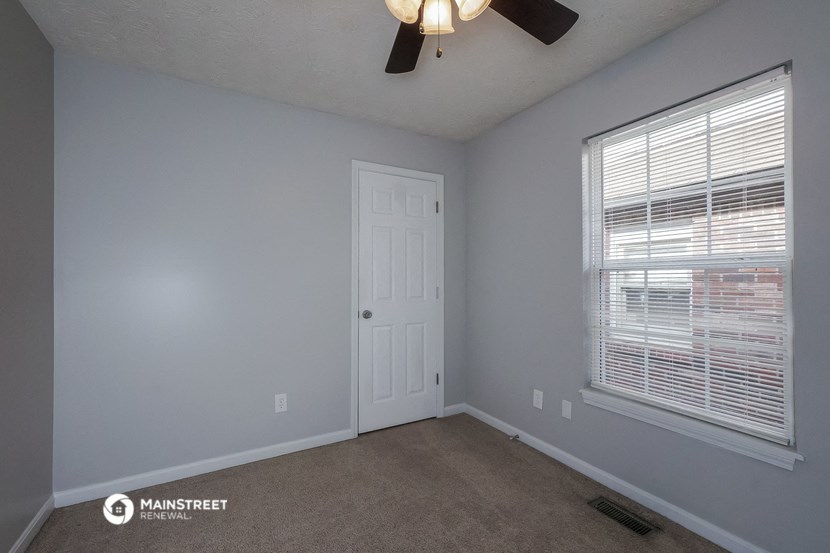 the bedroom has a ceiling fan and a large window