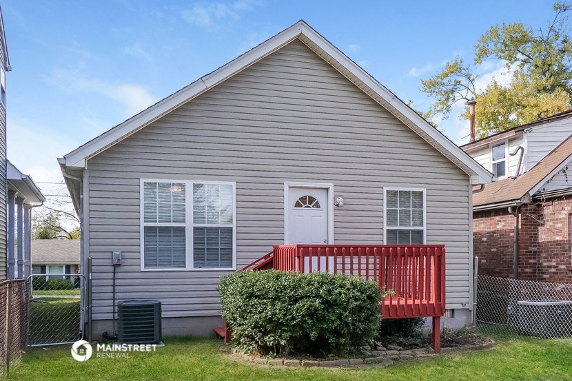 a red porch in front of a gray house with a red bench