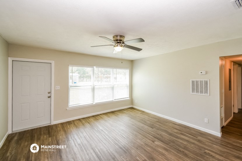 an empty living room with a ceiling fan and a door