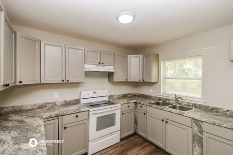 a kitchen with white cabinets and white appliances and marble counter tops
