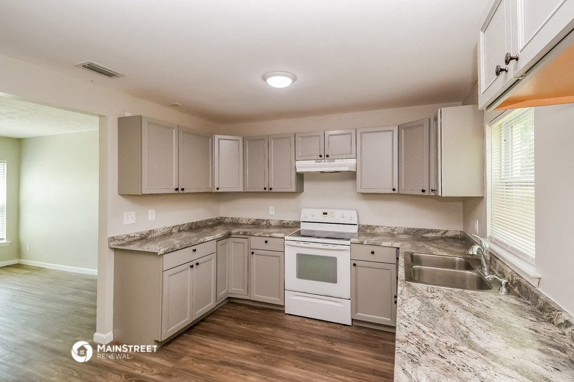 the kitchen of a rental home with white appliances and granite counter tops
