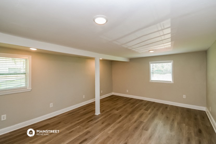 the spacious living room with hardwood flooring and a ceiling fan