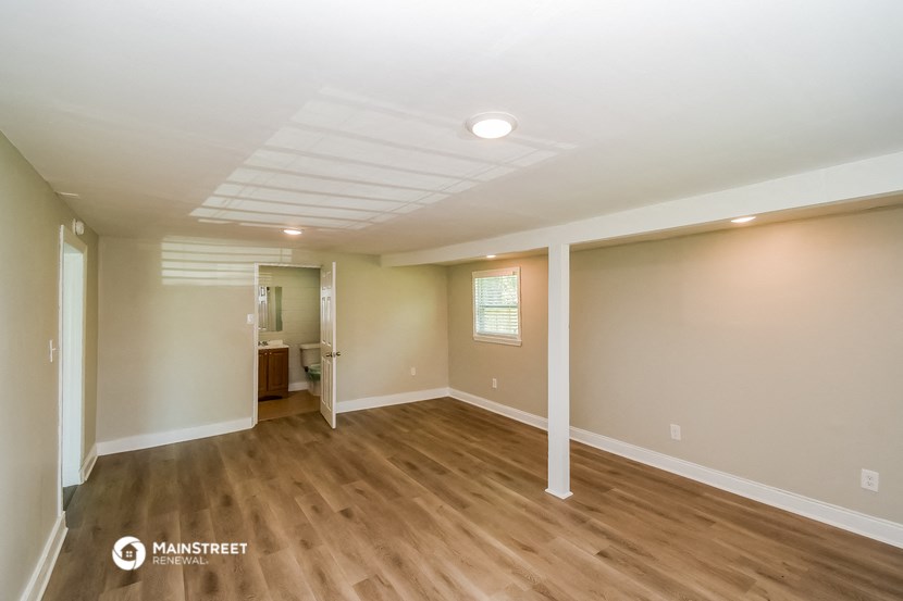 the spacious living room with wood flooring and white walls