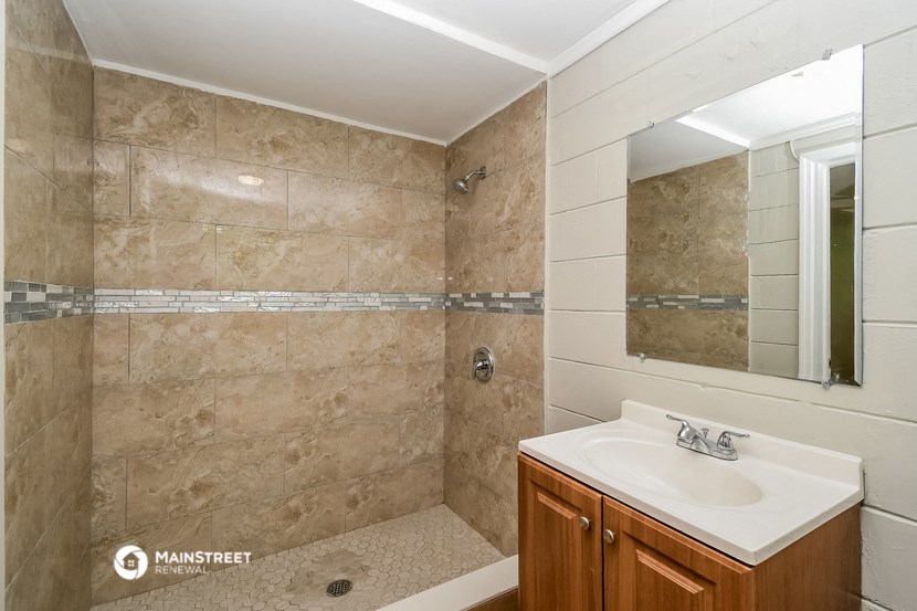 a bathroom with a sink and a shower and a mirror