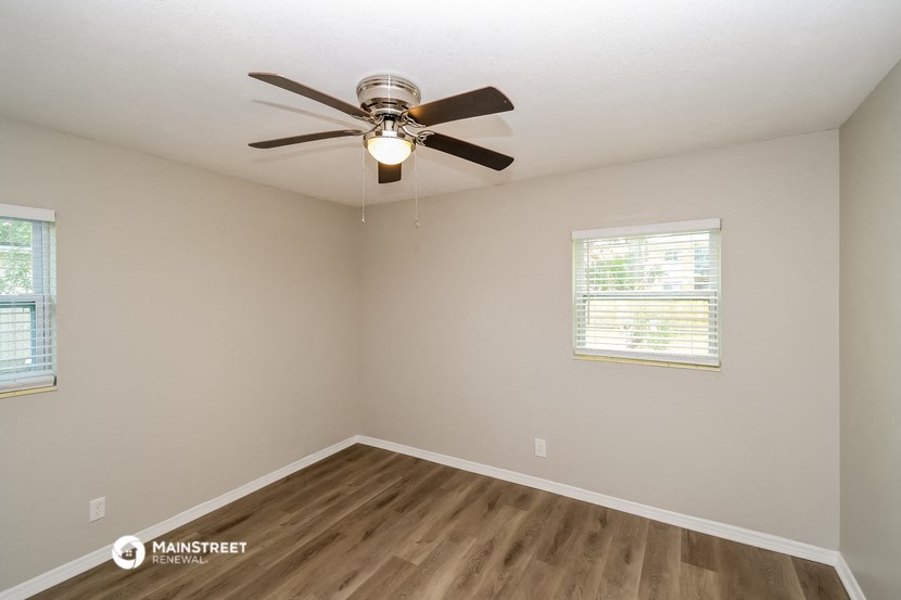 the spacious living room with ceiling fan and wood flooring
