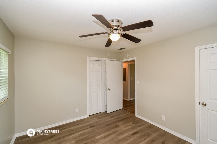 the spacious living room with ceiling fan and door to the closet