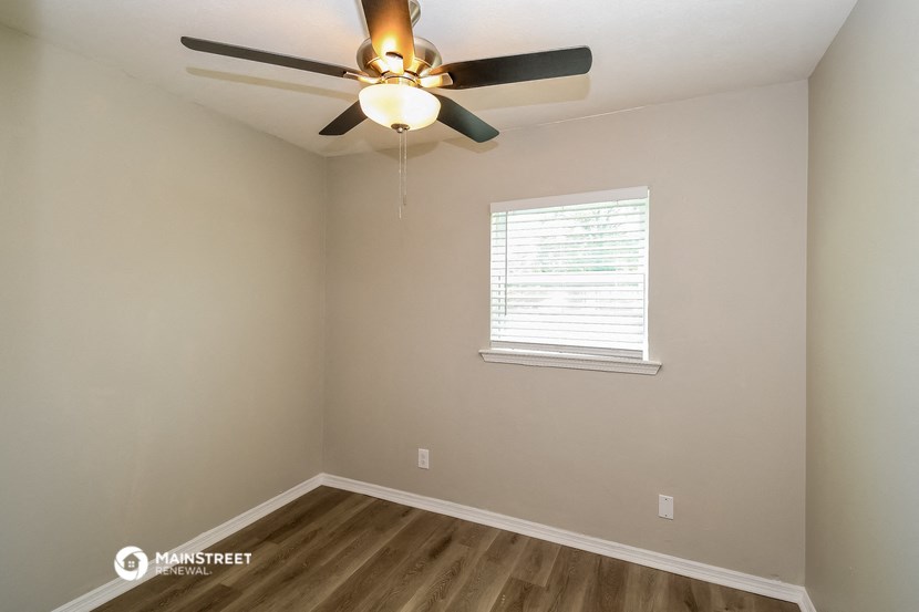 the interior of a bedroom with a ceiling fan and a window