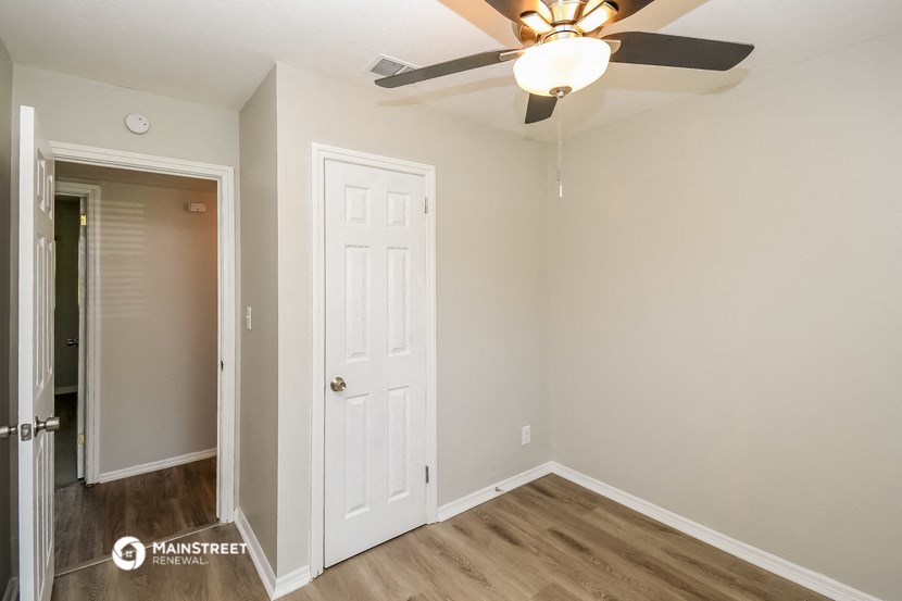 a bedroom with a white door and a ceiling fan