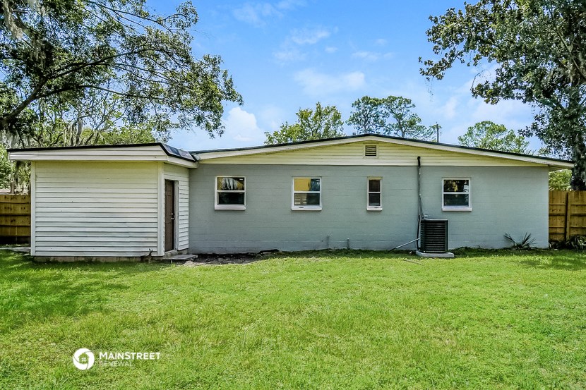 a small white house with a grassy yard and a tree
