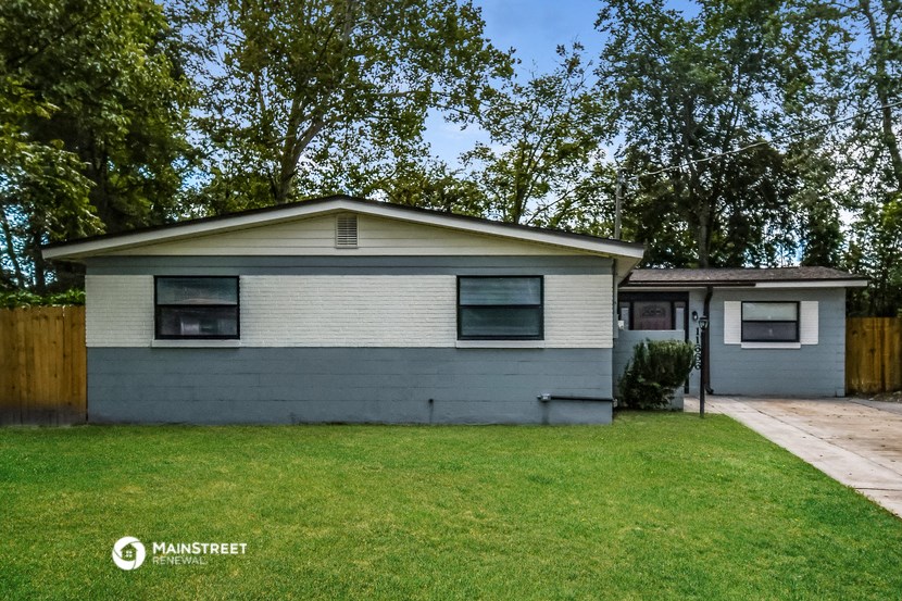 a small white and blue house with a yard and trees