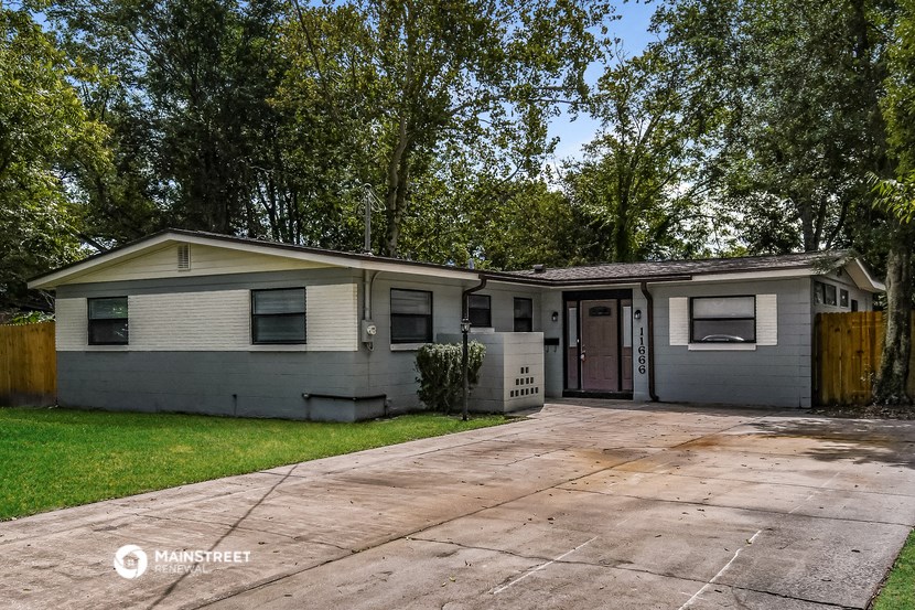 a gray house with a driveway and trees