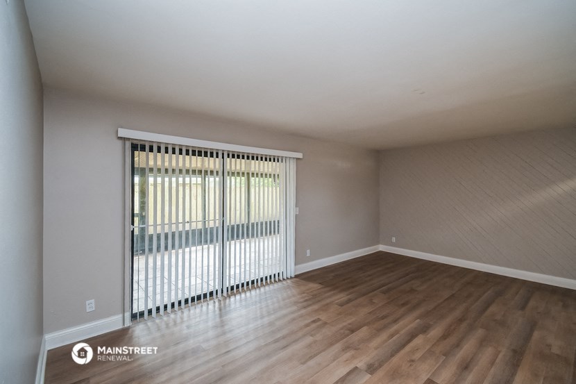 the living room of an apartment with wood floors and a sliding glass door