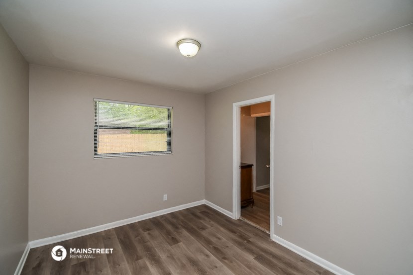 the interior of an empty room with wood flooring and a window