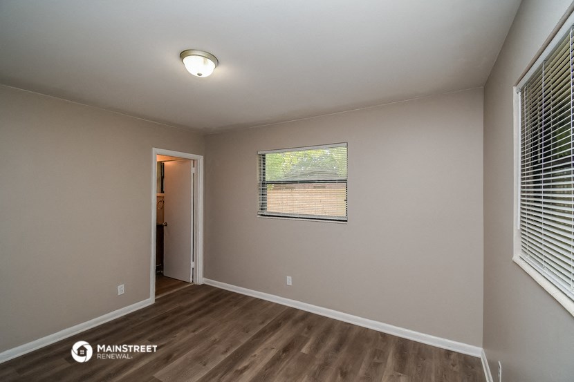 the interior of an empty room with wood flooring and a window