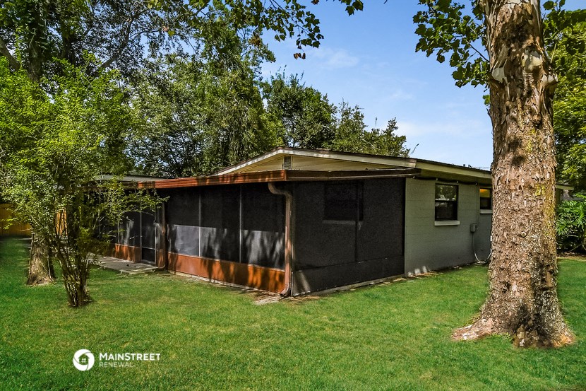 a small house with a screened in porch and a tree