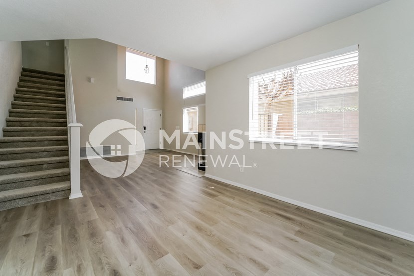 a renovated living room with a staircase and hardwood floors