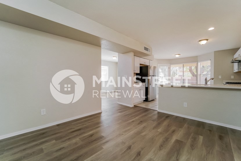 a renovated living room with a kitchen and hardwood floors