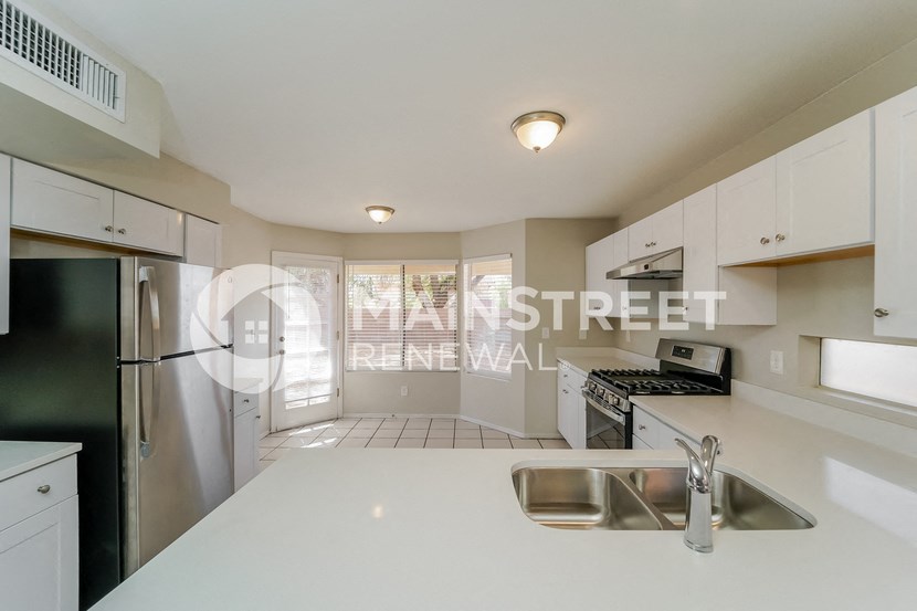 a renovated kitchen with white countertops and stainless steel appliances