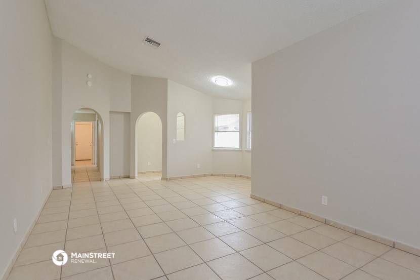 a spacious living room with tiled floors and white walls