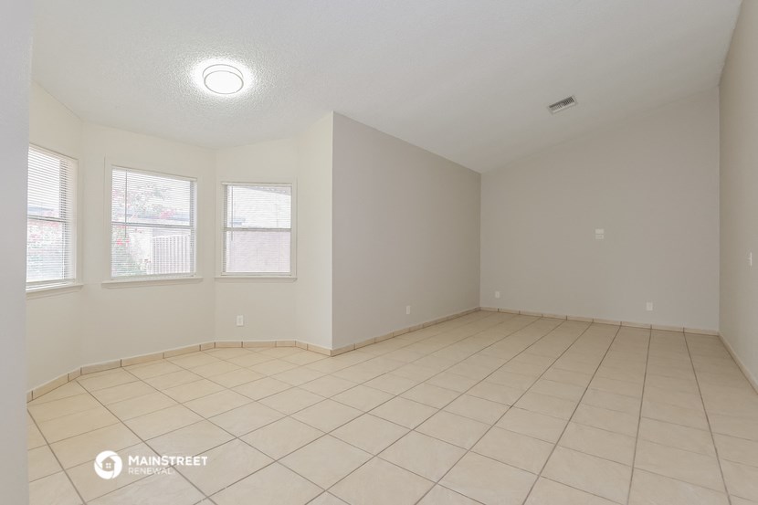 the living room of an empty house with a tiled floor and three windows