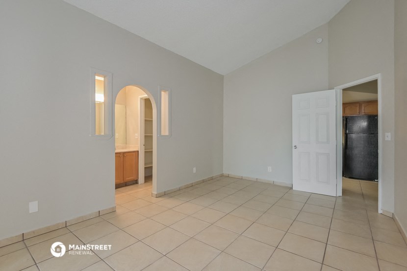 an empty living room with a door to the kitchen