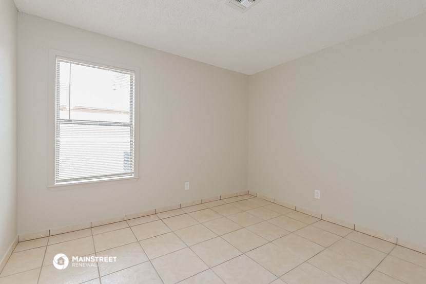the living room of an empty room with tiled floors and a window