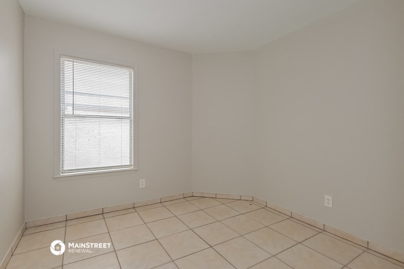the living room of an empty house with tiled floors and a window