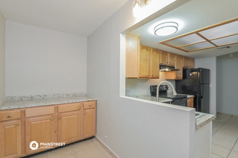 a kitchen with wood cabinets and a counter top and a black refrigerator