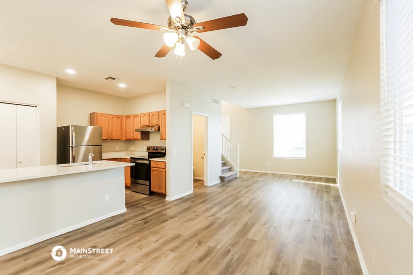 an empty living room and kitchen with a ceiling fan