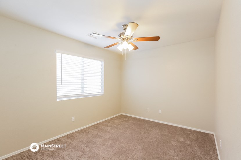 an empty room with a ceiling fan and a window