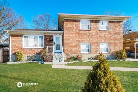 a brick house with a blue door and a lawn