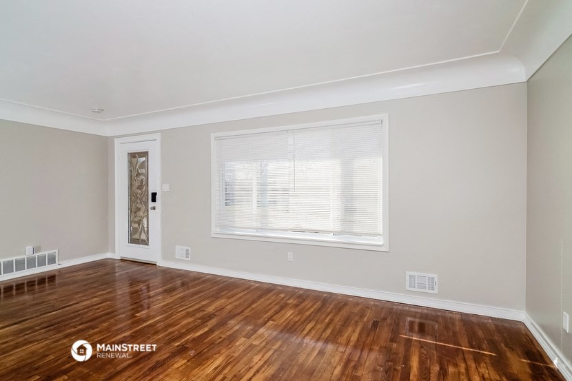 the living room with wood floors and a window
