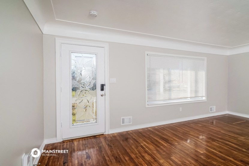 the living room of a home with a hardwood floor and a door to a