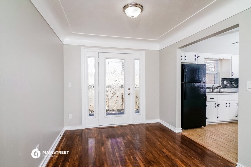 a living room with wood floors and a black refrigerator