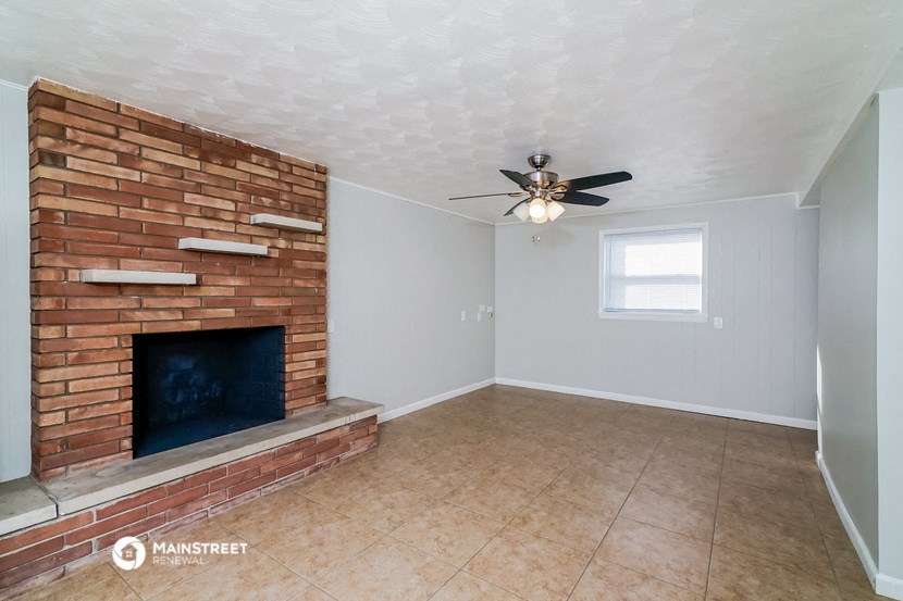 a living room with a brick fireplace and a ceiling fan