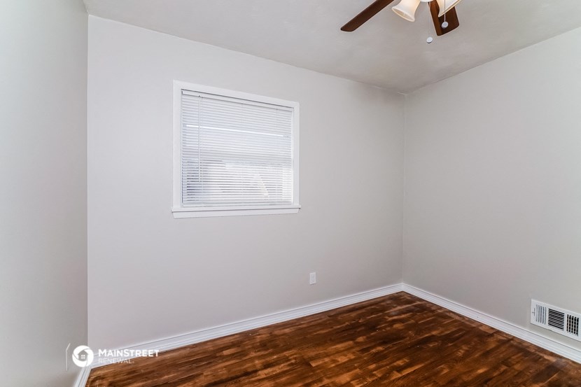 a bedroom with a wooden floor and a window and a ceiling fan
