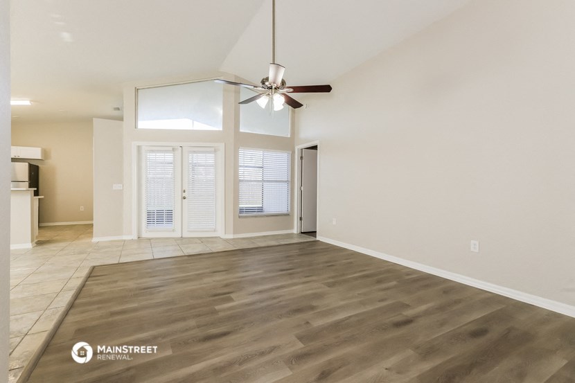 the spacious living room with wood flooring and a ceiling fan