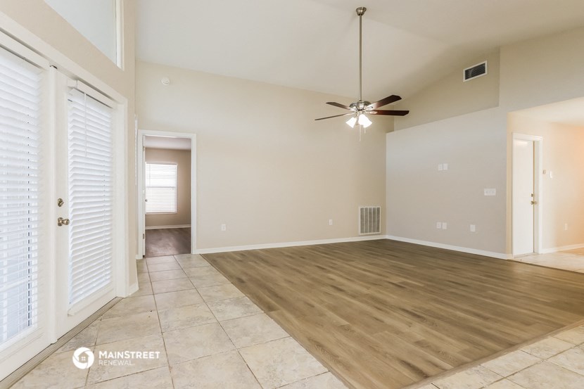the spacious living room with tile flooring and a ceiling fan