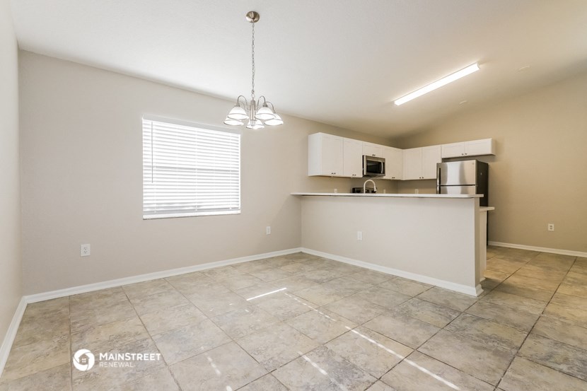 the spacious living room and kitchen with a large tiled floor