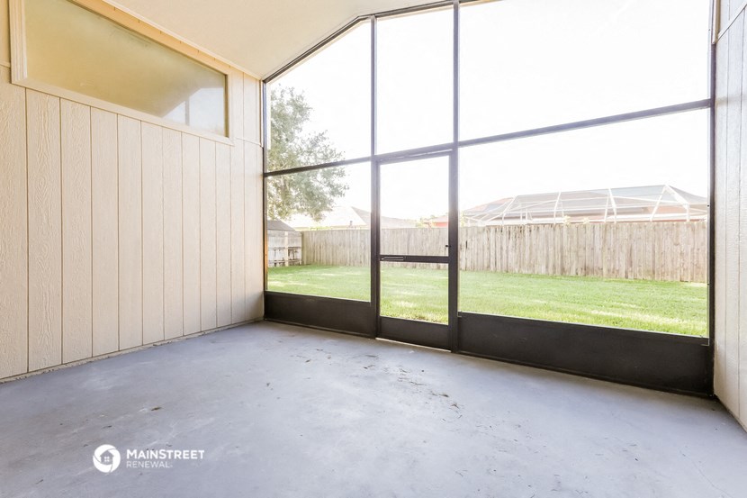 an empty room with large windows and a backyard