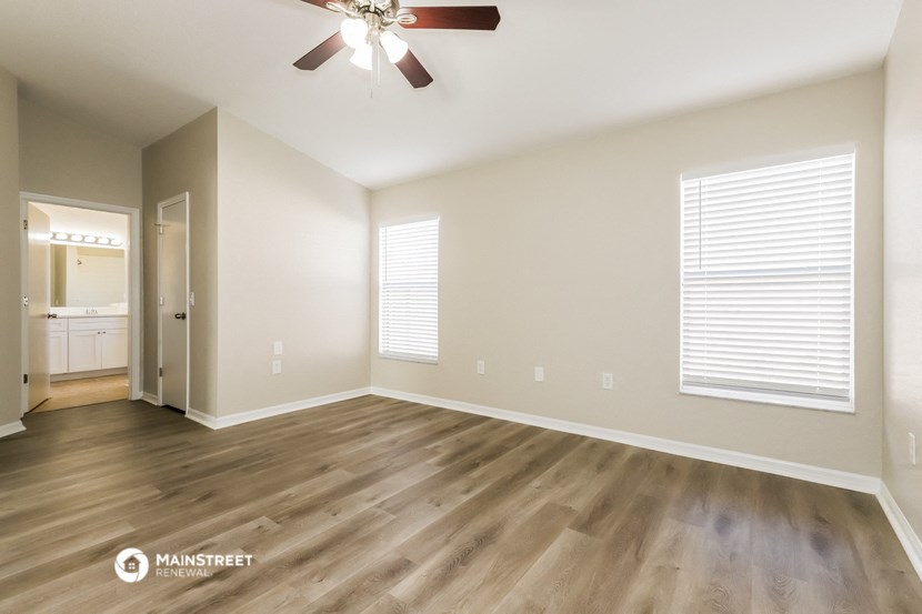 the spacious living room with hardwood flooring and a ceiling fan