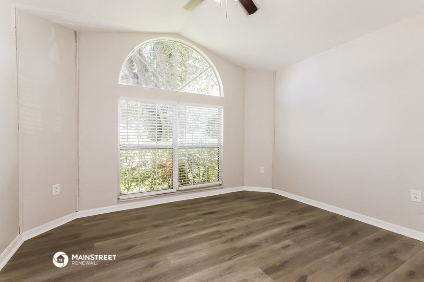 an empty room with a large window and wood flooring