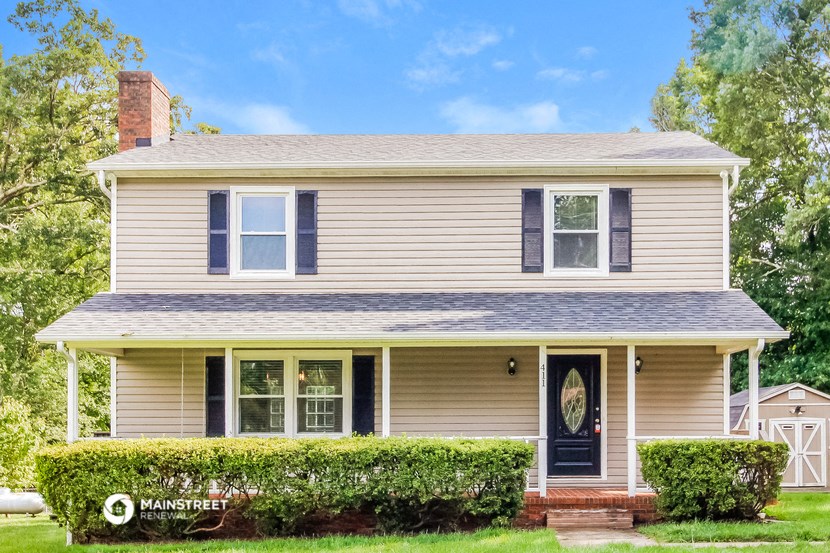 the front of a house with a blue door and a yard with bushes