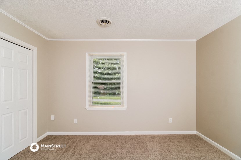 a empty room with a window and carpeting