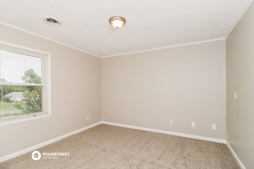 the spacious living room with carpet and a large window